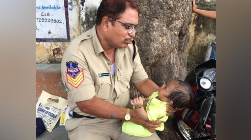Head Constable Officer Mujeeb-ur-Rehman (of Moosapet PS) who was on duty for conducting SCTPC exam in Boys Junior College, Mahbubnagar, trying to console a crying baby, whose mother was writing exam inside the hall, Rajeswari wrote alongside the image. (Photo: ANI)