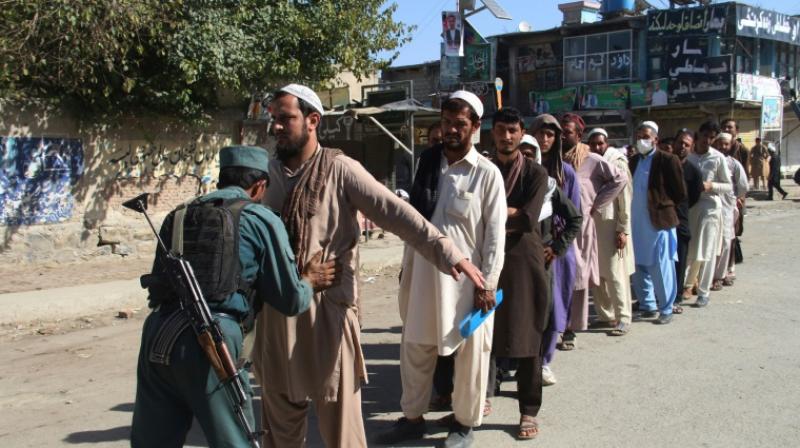 An Afghan policeman searches voters before casting their votes, with many voters having to queue for hours. (Photo: AFP)