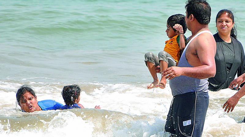 Parents with their children play in the blue waters at Rushi Konda Beach unmindful of the lurking danger in Visakhapatnam on Saturday. (Photo: DC)