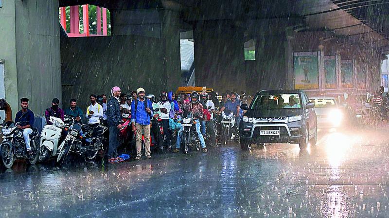 People take shelter under Metro pillars to protect themselves from getting drenched in rain. Left: There was massive waterlogging at Ranigunj circle in the city on Sunday due to rains.