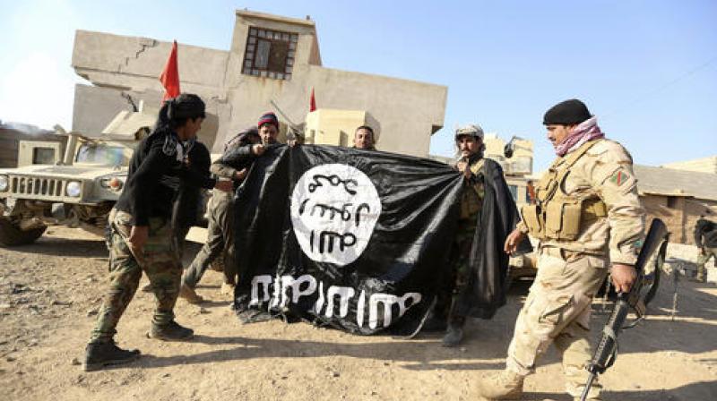 Iraqi Army soldiers celebrate as they hold a flag of the Islamic State group they captured during a military operation to regain control of a village outside Mosul, Iraq. (Photo: AP)