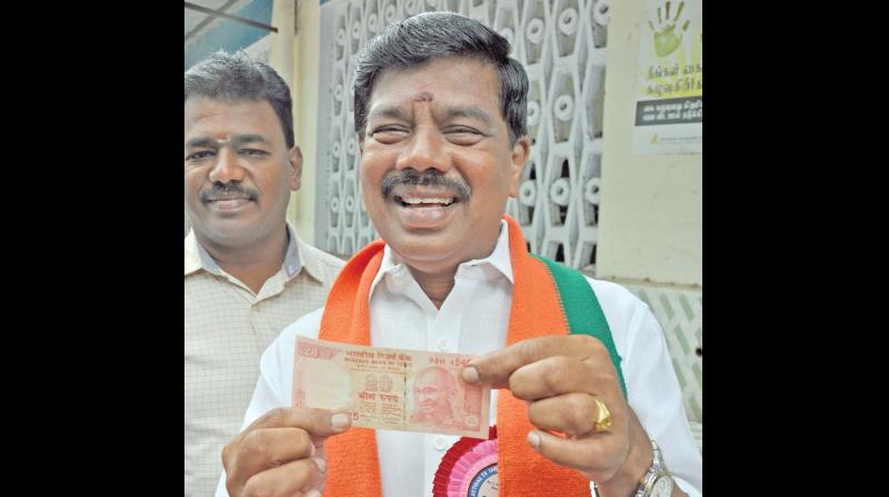 BJP candidate Karu Nagarajan displays a Rs 20 note distributed as a token for cash for vote. (Photo: DC)