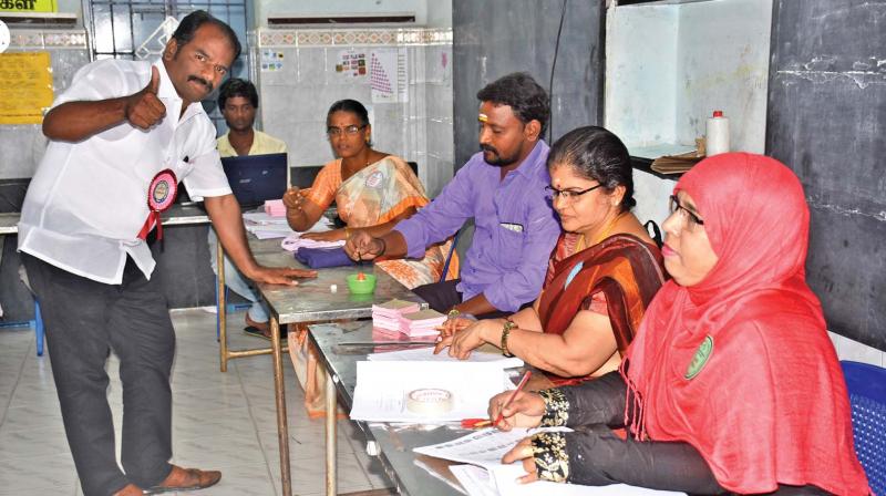 DMK candidate Marudhu Ganesh sports a victory sign while casting his vote.
