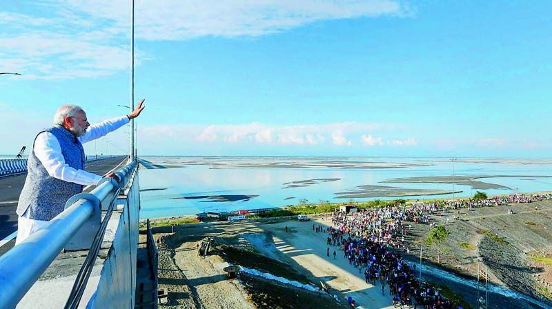 Prime Minister Narendra Modi waves at people from the Bogibeel Bridge, the longest rail-cum-road bridge on Brahmaputra river, after it was inaugurated by him, in Dibrugarh, Tuesday. Modi also flagged off two new Intercity Express trains connecting Tinsukia and Naharlagun via the Bogibeel Bridge. 	PTI