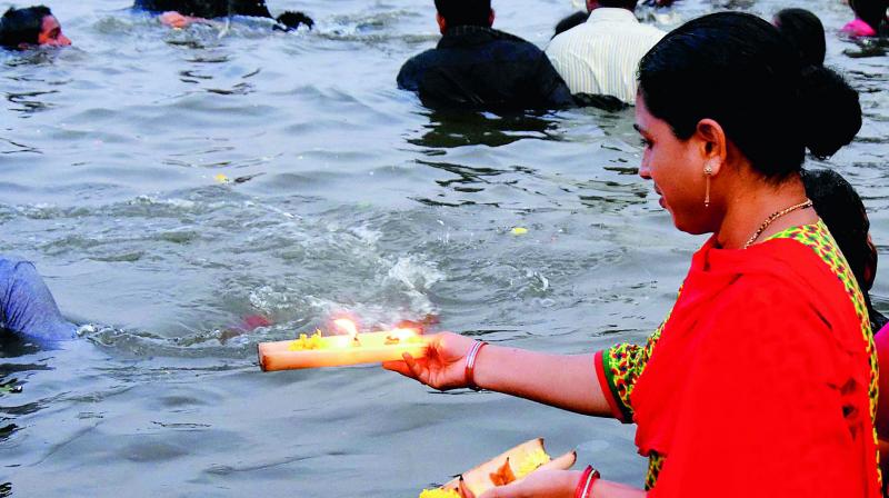 A woman releases diyas in the River Krishna at Durga ghat on the occasion of Karthika Pournami in Vijayawada on Friday.  (Deccan chronicle)