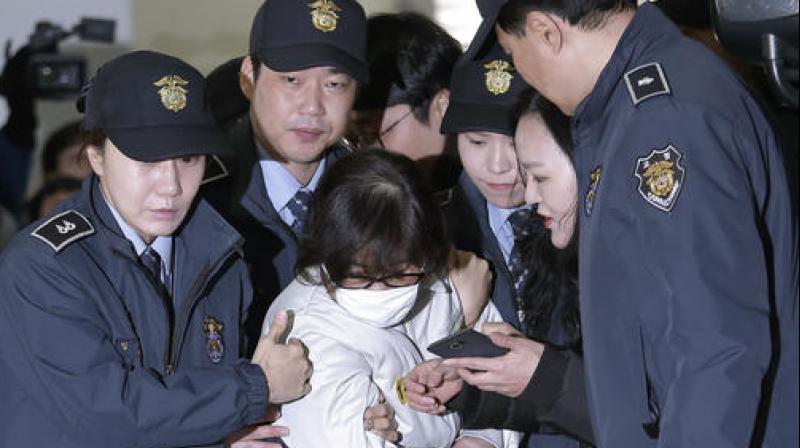 In handcuffs, white prison clothes and a surgical mask, Choi Soon-sil was escorted into a southern Seoul office where investigators have been widening their inquiry into the scandal. (Photo: AP)