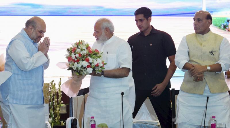 Prime Minister Narendra Modi being greeted by BJP President Amit Shah as Home Minister Rajnath Singh looks on at a meeting of National Democratic Alliance at Pravasi Baratiya Kendra in New Delhi. (Photo: PTI)