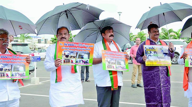 BJP legislators stand in front of the AP Assembly with umbrellas and wearing a raincoat, on Thursday. (Photo: DC)