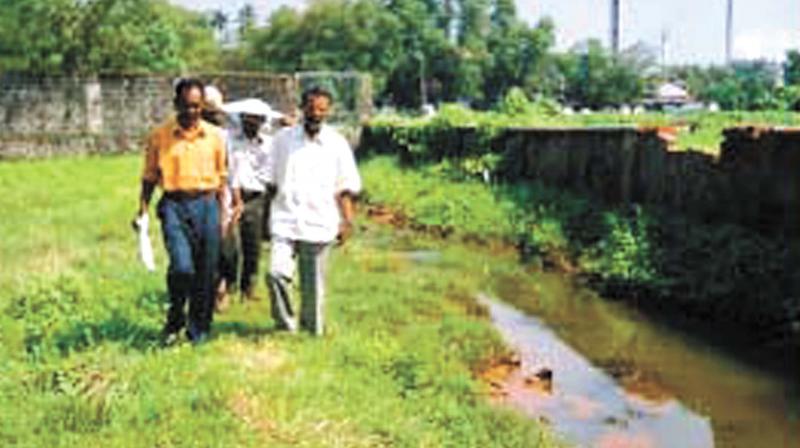 People walk along the highly polluted Kuzhikandam creek.