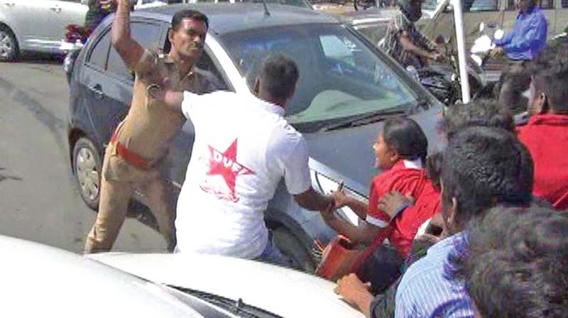 A policeman beats up protesting DYFI  workers in Medavakkam on Saturday. (Photo: DC)