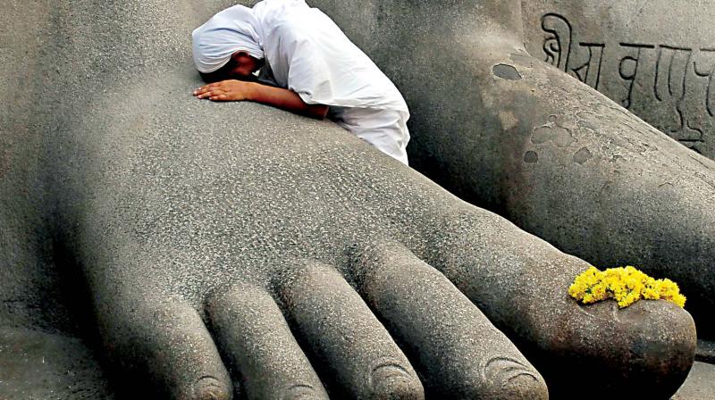 A Jain monk at the feet of the gigantic statue of Lord Bahubali during the Mahamastakabhisheka at Shravanabelagola.