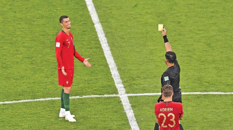 Paraguayan referee Enrique Caceres shows the yellow card to Portugals forward Cristiano Ronaldo during the Russia 2018 World Cup Group B football match between Iran and Portugal.
