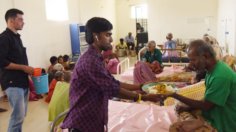 A volunteer offers food to an aged person who was made to wait for several hours the Home sheltering them was asked to move out.  (Deccan Chronicle)