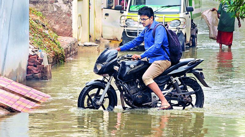 A biker wades through stagnant water on Friday at Anand Bagh in Malkajgiri, following heavy rains in the city on Thursday night. (Deepak Deshpande)