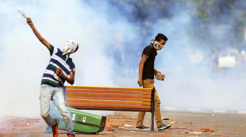 A student throws a teargas canister towards security personnel in central Srinagars Lal Chowk on Tuesday. The police fired into a crowd of stone-throwing students in Kashmir as violence in the region intensified. (Photo: AFP)