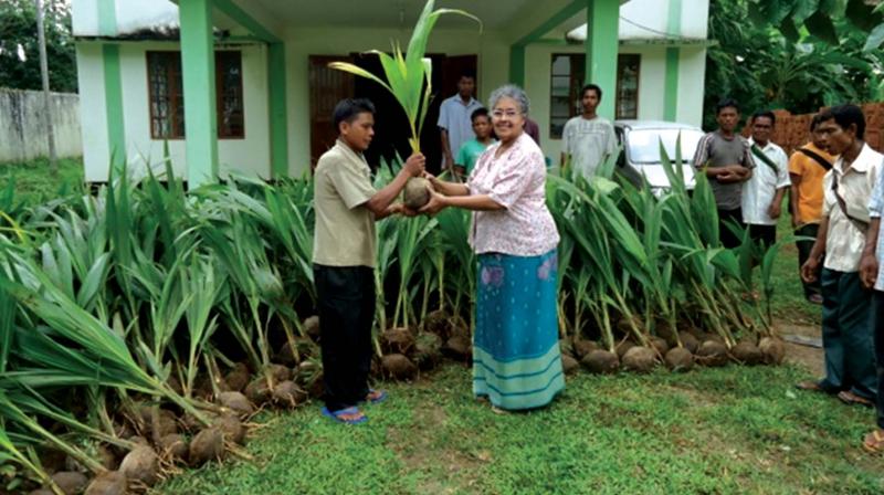 Sister Rose hands over coconut saplings to villagers.