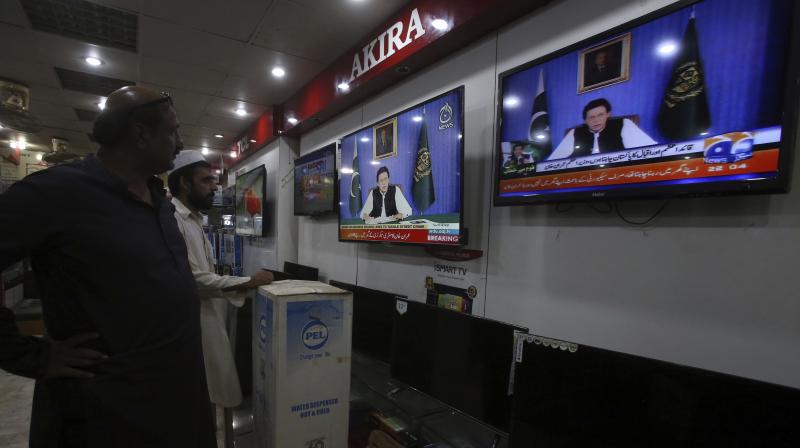 People watch a televised address of Pakistans newly elected Prime Minister Imran Khan at an electronic shop in Karachi on Sunday. (Photo: AP)