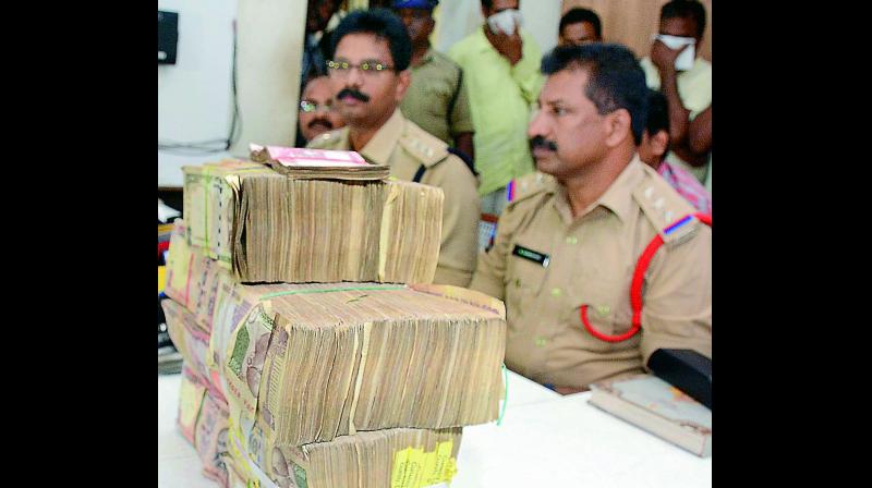 ACP M. Satyanandam and CI Damodar display the banned currency notes, amounting to Rs 50 lakh, at the media conference in Vijayawada on Monday. (Photo: DC)