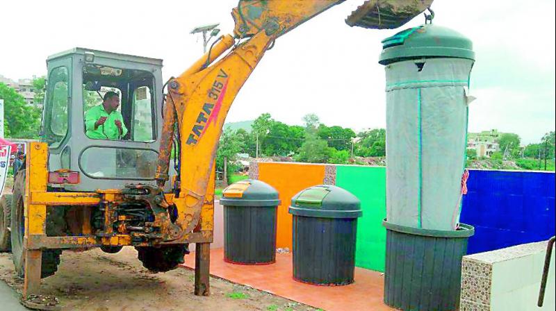 Workers clear an e-dust bin near Andhra Loyola College in Vijayawada, placed as part of a pilot project. (Photo: DC)