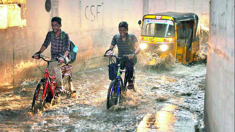 Students make their way through stagnated water at Kankaragunta road under bridge in Guntur city on Monday. (Photo: DC)