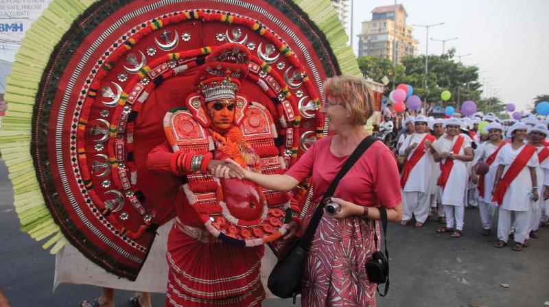 A foreigner shakes hands with a Theyyam artiste as part of the New Year celebration rally organised by City Service Cooperative Bank on Saturday on Kozhikode beach. (Photo: Akhin Dev)