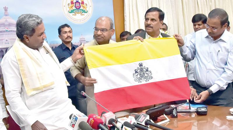 Chief Minister Siddaramaiah with Kannada Sahitya Parishat president Manu Baligar and Kannada Development Authority chairman Prof S.G Siddaramaiah among others with the proposed new Kannada Flag in Bengaluru on Thursday 	 DC