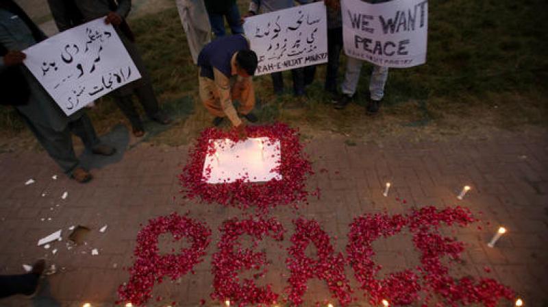 A Christian adjusts a candle next to wording Peace drawn with rose petals during a candlelight vigil for the victims of an overnight attack on the Quetta Police Training Academy, in Islamabad, Pakistan. (Photo: AP)