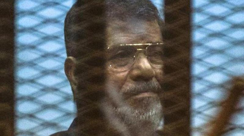 Egypts deposed Islamist president Mohammed Morsi sits behind the defendants cage. (Photo: AFP)