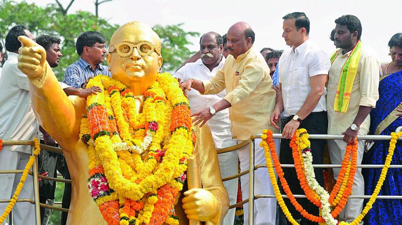 Minister for Roads and Buildings Ch. Ayyanna Patrudu pay floral tributes to the statue of social reformer Dr B.R. Ambedkar during the 126th birth anniversary celebrations at Dabagardens in Visakhapatnam on Friday. 	(Photo: DECCAN CHRONICLE)