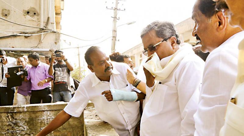 Chief Minister Siddaramaiah covers his nose during an inspection of rain-affected areas in Bengaluru on Wednesday	(Photo:DC)