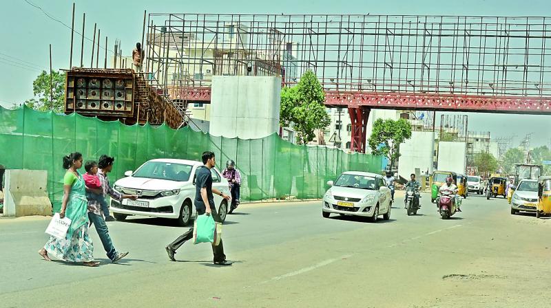 Pedestrians cross the road instead of using the foot overbridge at Raidurg on Saturday.  	  Image;  S. Surender Reddy