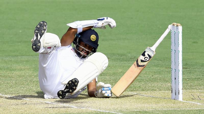 Karunaratne slumped to the ground, dropping his bat as Australian players ran to assist. (Photo: AFP)
