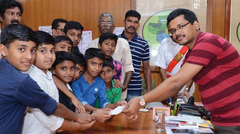 Children from Gandhi Smaraka Football Academy, Chulliode, hands over the amount they collected for relief works to District Collector Kesavendra Kumar at Kalpetta, Wayanad on Tuesday.