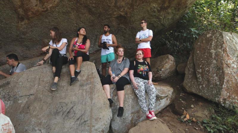 Members of the Kerala Blog Express Team resting on large rock boulders during a forest trek in Wayanad.