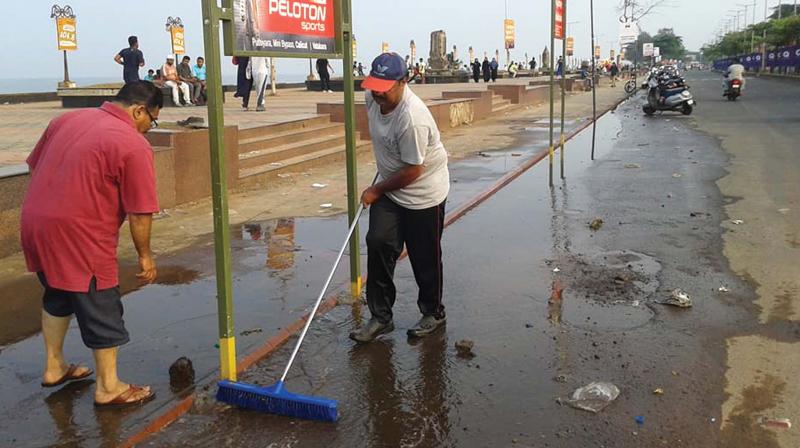 Team Clean Beach members Arun Das and P.V. Mohammed Salih clean the road in front of the Corporation office on Monday. (Photo: DC)