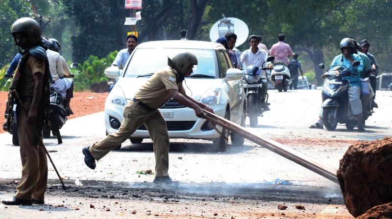 Police tries to clear the road which was rampaged by protesters near Vengara on Friday. 	(Photo: DC)