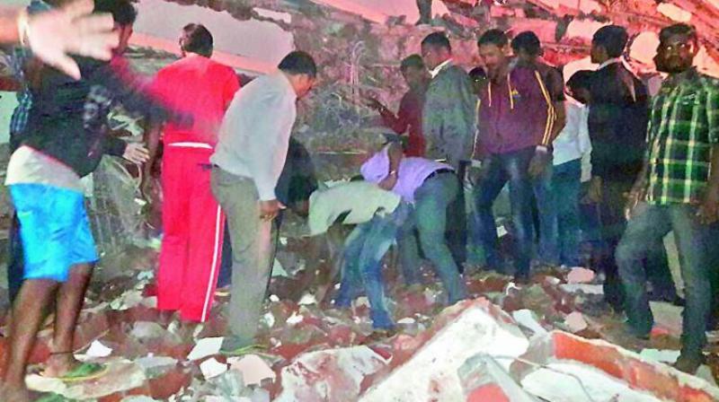 Locals and rescue workers search for bodies feared buried under the debris of a collapsed five-storey building at Nanakramguda on Thursday. (Photo: DC)
