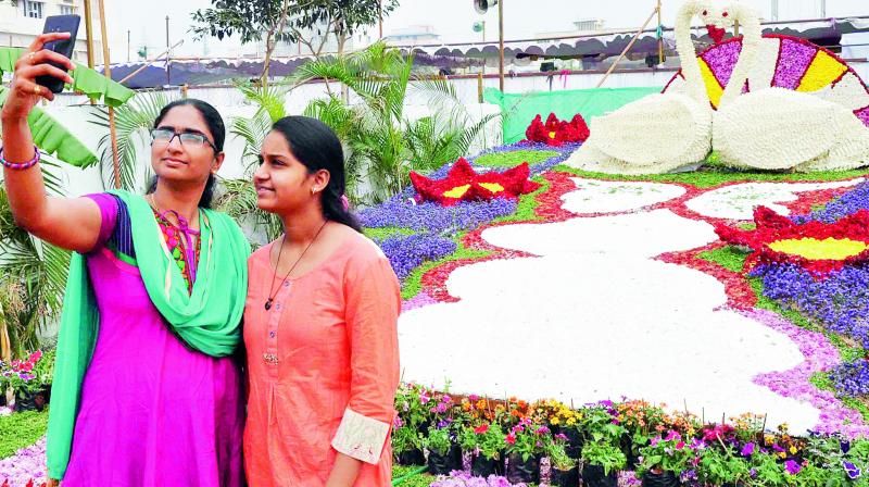 Girls take a selfie at the rose exhibition at Guru Nanak Colony in Vijayawada on Thursday. 	(Photo: DC)