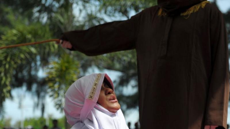 A religious officer canes a woman for spending time in close proximity with a man who is not her husband in Banda Aceh, Indonesia, on November 28, 2016. (Photo: AFP)