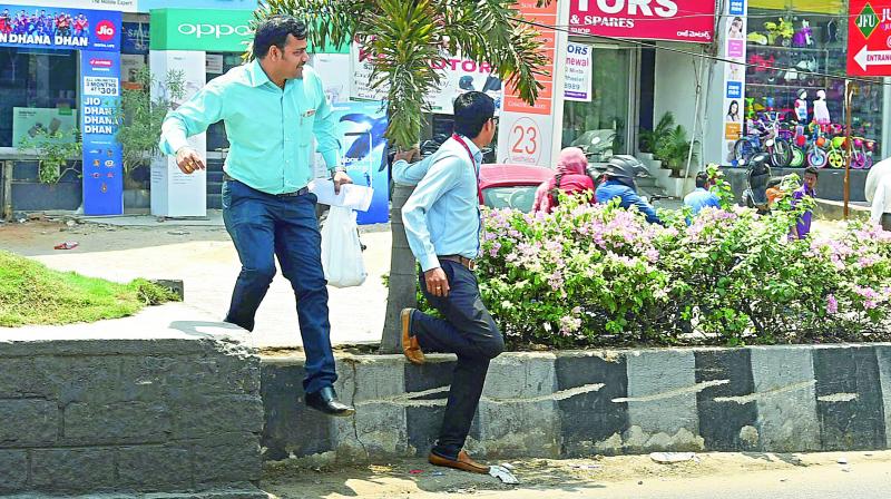 Pedestrians have to jump the divider at Kondapur as there are no gaps for them to cross the road. DC