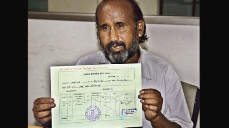 Shanmugavel shows his patta document. (Photo: DC)