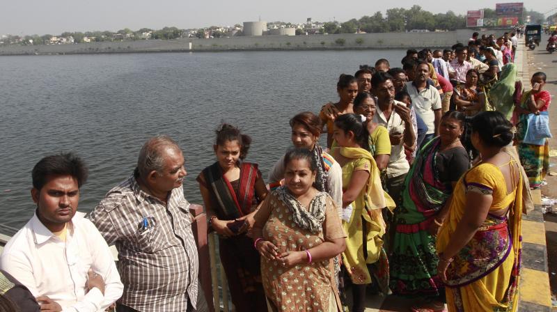 People stand over a bridge across River Sabarmati as they wait in a queue to deposit and exchange discontinued notes in Ahmedabad. (Photo: AP)