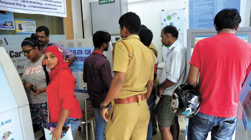 A cop watches as people withdraw cash from an ATM counter near Statue Junction in Thiruvananthapuram on Sunday. Since most of the ATMs ran out of money in the city in no time, heavy rush was experienced at ATMs which had been stacked with cash. (Photo: DC)