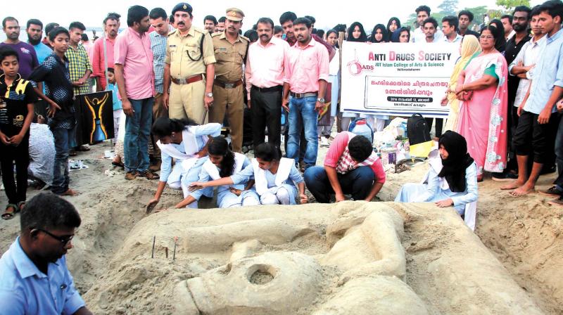 Students of JDT Arts and Science College make a sand sculpture on Kozhikode beach on Sunday. Also seen are Excise Joint Commissioner T. Jayaraj and CI M.K. Gireesh