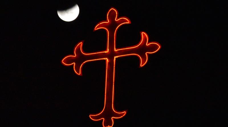 Lunar eclipse seen in the backdrop of a Cross in Secunderabad on Wednesday night. 	(Photo: DC)