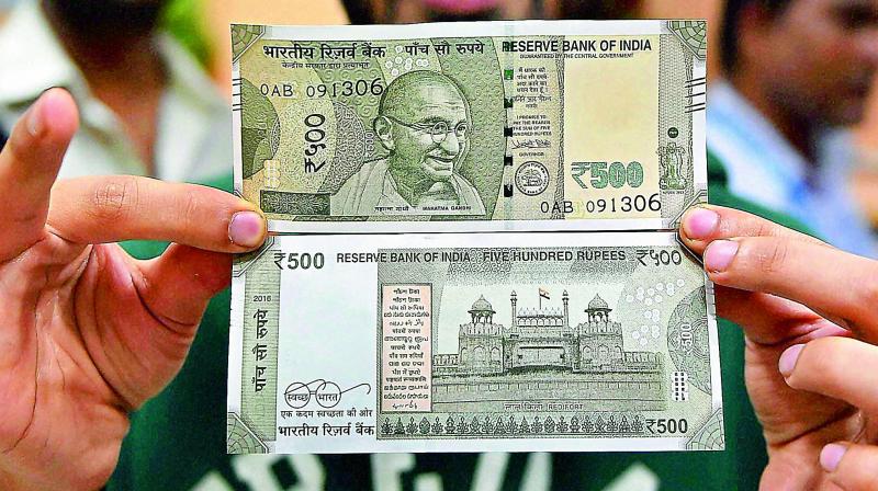 A customer shows off the new Rs 500 banknote, introduced over the weekend, at a bank in New Delhi on Sunday.(Photo: PTI)