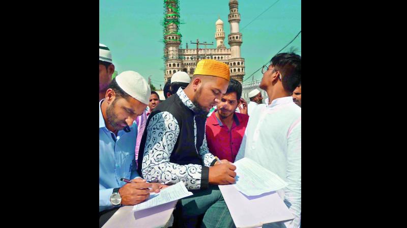 Muslims participate in a signature campaign against Uniform Civil Code at the Macca Masjid in Hyderabad after Friday prayers. 	(Photo:Deccan chronicle)
