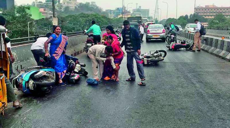 Bikers skid after losing balance on the oil spilt Telugu Talli flyover on Friday.   	Deccan Chronicle