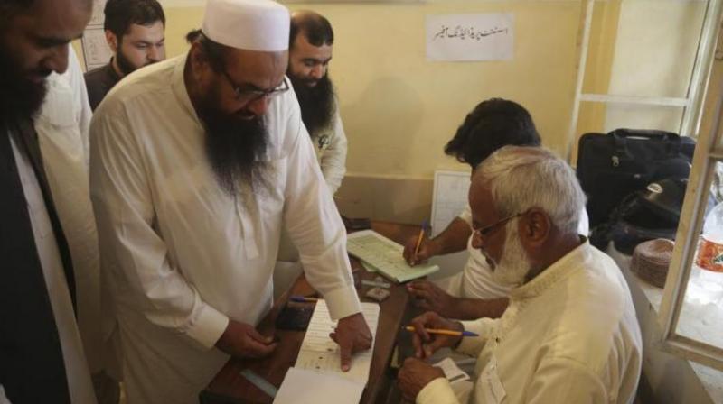Hafiz Saeed, center, head of the Pakistani religious party Jamaat-ud-Dawa, affixes his thumb impression before casting a vote in Lahore, Pakistan, Wednesday, July 25, 2018. (Photo: AP)