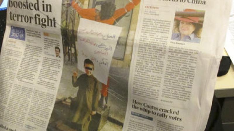 This photo published on the front page of the Monday, May 9, 2017, edition of \The Australian\ newspaper shows says a 6-year-old Australian boy making an Islamic State movement salute in front of a human body hanging from a cross. (AP Photo)
